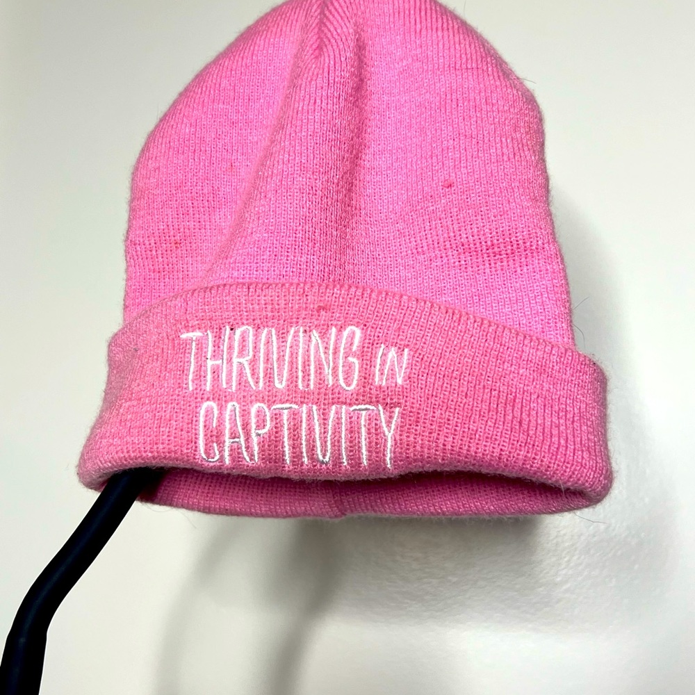 ‘Thriving in captivity’ pink beanie